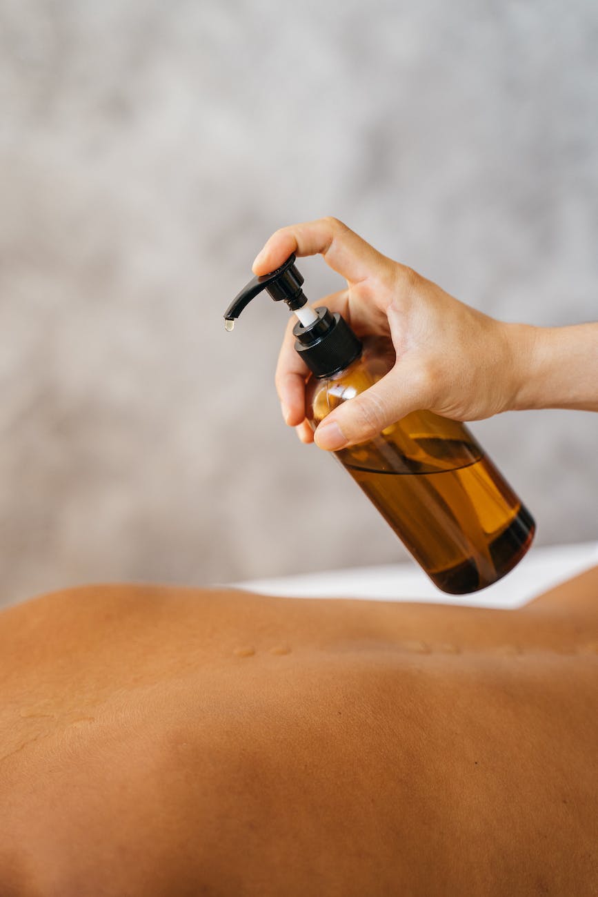 a massage therapist putting oil on a client s bare back